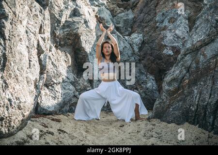 Slim female with raised arms performing Vrikshasana pose on yoga