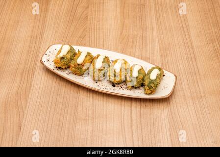 Croquettes stuffed with spinach battered with bread ready to serve as Spanish tapas on wooden table Stock Photo