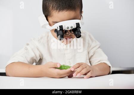 A little boy exploring slime structure with head magnifying glasses headset Stock Photo