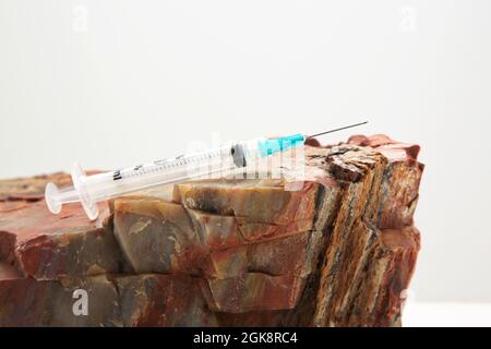 Injection needle on rock reflects solid public health recommendations with firm data to support vaccine guidance in conceptual image