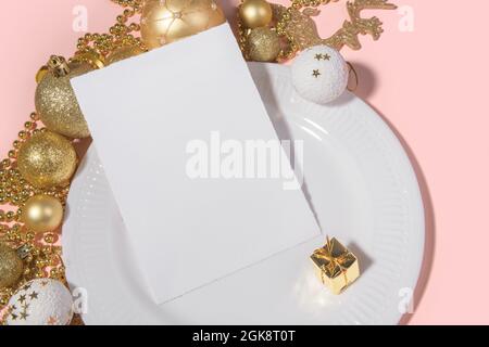 Christmas vertical 5x7 card mockup torn edges with table setting white plate and golden decoration on pink background. Festive modern restaurant menu, Stock Photo