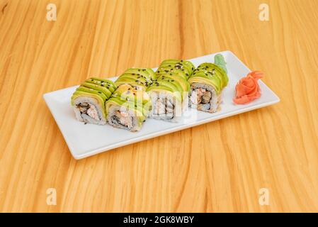 uramaki dragon roll with wasabi and ginseng with avocado slices on top, stuffed with eel and cheese with sesame and poppy seeds. Stock Photo