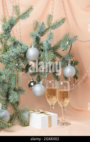 Christmas. A New Year's composition made of branches of a Christmas tree decorated with silver balls, a gift box, sparkling wine glasses on a backgrou Stock Photo