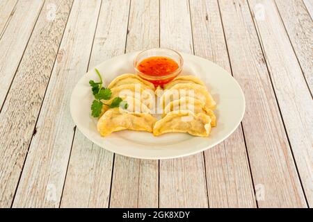 Recipe of traditional Chinese kuo tie dumplings cooked on the grill accompanied by sweet and sour sauce to dip on a white table Stock Photo