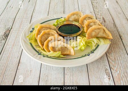 Portion of grilled gyozas with soy sauce in a Chinese restaurant with white tables Stock Photo