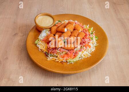 salad with chopped mozzarella cheese fingers, diced ham, shredded cheese and iceberg lettuce with curry sauce on a clay colored plate Stock Photo