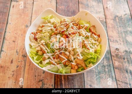 white bowl with typical Caesar salad with lettuce, chicken pieces and croutons Stock Photo
