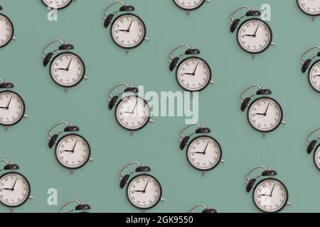 Pattern composition of  black antique alarm clock on green background. Flat lay composition. Top view. Stock Photo