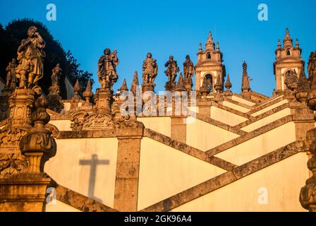 Zigzag shaped staircase of the church with numerous different statues and a cross shadow - Bom Jesus do Monte, Braga, Portugal, Vertical Stock Photo