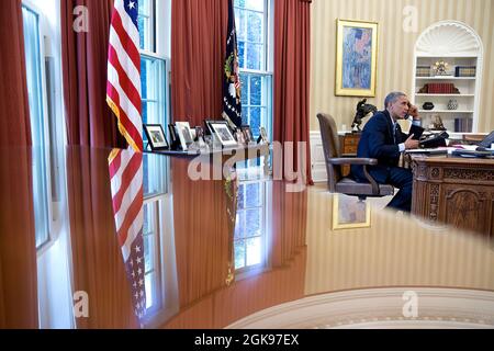 President Barack Obama talks on the phone with President François Hollande of France in the Oval Office, Aug. 9, 2014. (Official White House Photo by Pete Souza) This official White House photograph is being made available only for publication by news organizations and/or for personal use printing by the subject(s) of the photograph. The photograph may not be manipulated in any way and may not be used in commercial or political materials, advertisements, emails, products, promotions that in any way suggests approval or endorsement of the President, the First Family, or the White House. Stock Photo