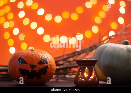 Branches, candle and Halloween pumpkins on an orange background with bokeh. Copy space. Stock Photo