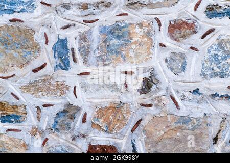 Background texture of wall made of colored stones with white putty. Ancient method of masonry walls. Stock Photo