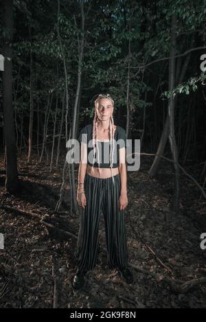 Young goth girl standing alone in a dark forest Stock Photo