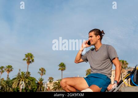 Young latin man with crutches using mobile phone after doing exercise Stock Photo