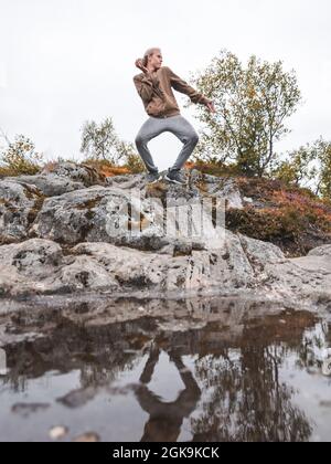 Long-haired Caucasian man posing on a hill in front of the lake Stock Photo