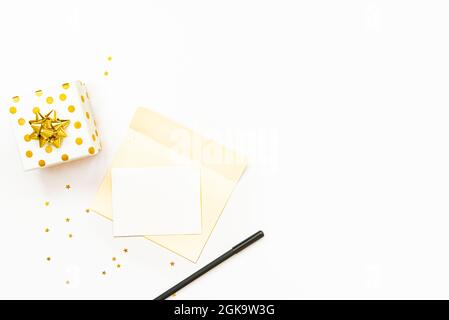 Top view of golden dotted gift box and open envelope with empty card on a white background. Copy space, mock-up. Stock Photo