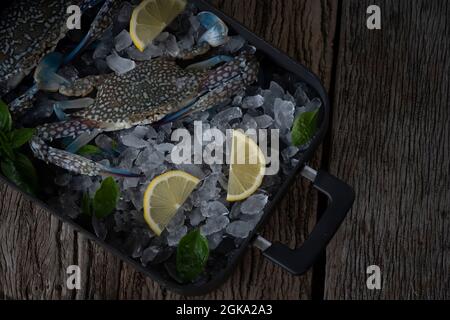 Seafood overhead shot. Fresh crab prawns on ice and wooden background. Stock Photo