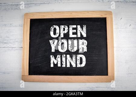 Open Your Mind. Chalk board on a white painted wooden background. Stock Photo
