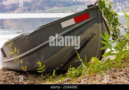 Front view of a fishing boat tied with chain on the shore of a lake. Selective focus, travel photo, street view, nobody. Stock Photo