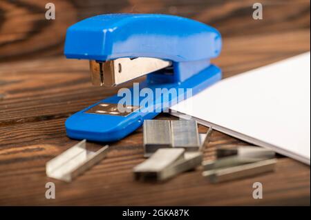 Office stapler, stapler staples and white paper on the table, close-up, selective focus Stock Photo
