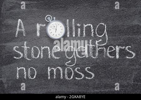 A rolling stone gathers no moss - English proverb  written on chalkboard with vintage precise stopwatch Stock Photo