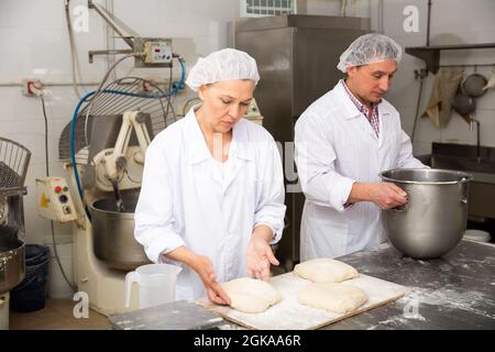 Female baker forming bread loaves from dough Stock Photo