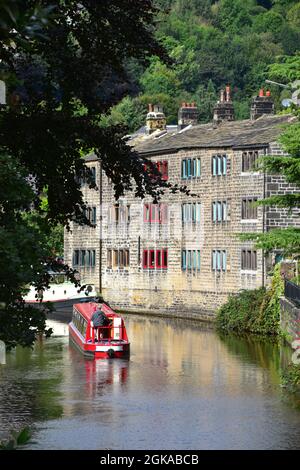 Narrowboat sailing past weavers cottages reflected in the Rochdale Canal, Hebden Bridge, Calderdale, West Yorkshire Stock Photo