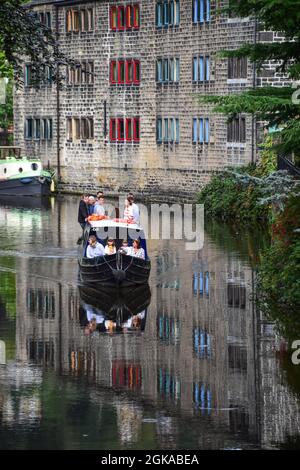 Narrowboat sailing past weavers cottages reflected in the Rochdale Canal, Hebden Bridge, Calderdale, West Yorkshire Stock Photo