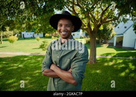 Mixed race male farmer standing outdoors with arms crossed Stock Photo