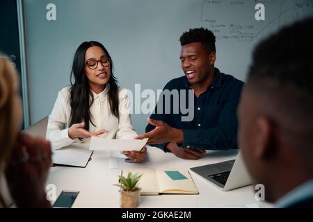 Multiethnic young man and woman having meeting at desk discussing the project in office Stock Photo