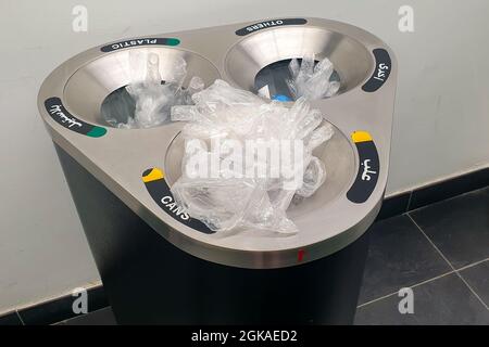 A trash can overflows with plastic disposable gloves in front of the supermarket in Dubai, UAE, plastic pollution due to COVID-19 pandemic. Stock Photo