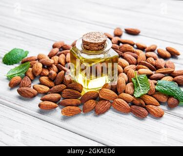 Almond oil and  almonds on white wooden background. Top view Stock Photo