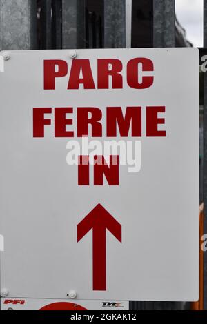 A white sign with red writing directing people to parc ferme Stock Photo