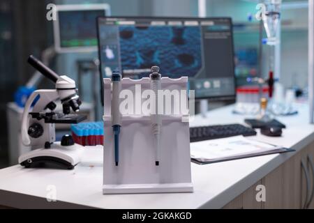 Nobody in research laboratory with micro pipette on desk. Empty scientific development place with microscope and chemical equipment and lab glassware. Biochemistry cabinet with tools Stock Photo