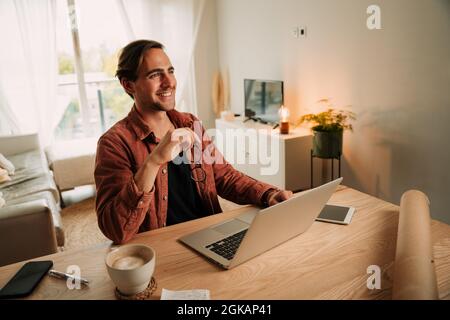 Caucasian male student working from home smiling while typing on laptop  Stock Photo