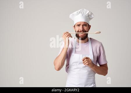male professional chef in apron holding a spoon cooking food service Stock Photo