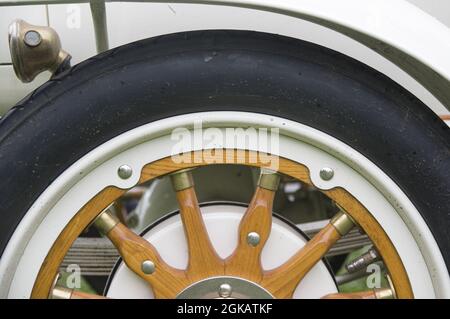 Close-up of tire and elegant refined wheel made of wooden and steel in white colour. Part of white gold antique retro vintage classic sport renovated car 1914 on exhibition Stock Photo