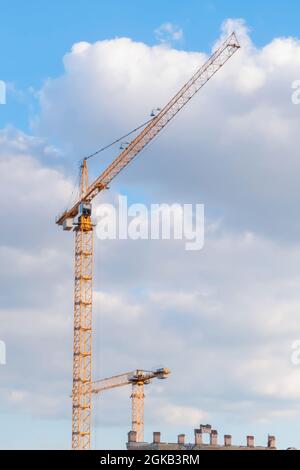 Yellow tower construction cranes against cloudy sky Stock Photo