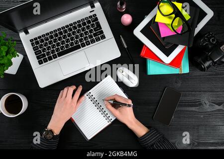 Mix of office supplies and gadgets on a wooden desk background. View from above. Stock Photo