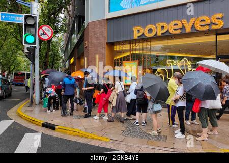 Shanghai, Shanghai, China. 14th Sep, 2021. On September 14, 2021, Shanghai, the storm brought by Typhoon ''Chanthu'' is still going on, but at the door of the main store in ''Guangming Village'' on Huaihai Middle Road, there are still many citizens waiting in the rain to buy fresh meat mooncakes. Citizens in line on Huaihai Middle Road stretched to the intersection of Chengdu South Road on the side. Some citizens also sat on the sidewalk with small stools and waited. Credit: ZUMA Press, Inc./Alamy Live News Stock Photo