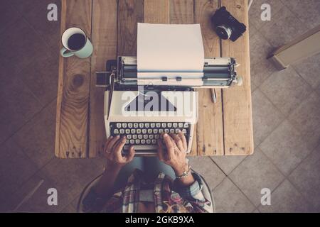 Top view of woman hands typing on typewriter keypad on paper. Woman typing on old typewriter keypad at office desk with coffee mug and camera on table Stock Photo