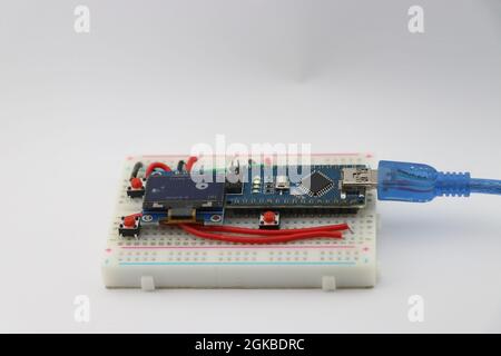 small display module showing some graphics from a game prototype project controlled by microcontroller board and small buttons in a breadboard Stock Photo