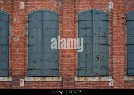 Closed iron window shutters in a historic red brick building. Stock Photo