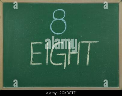 Number eight written in chalk on the school board. Stock Photo