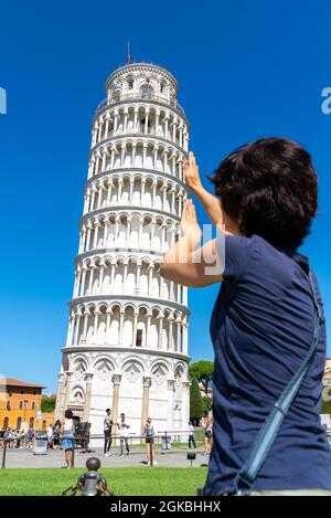 PI, ITALY - Aug 22, 2020: A typical tourist image of the Leaning Tower of Pisa, where the tourist looks as if he is supporting the tower. Stock Photo