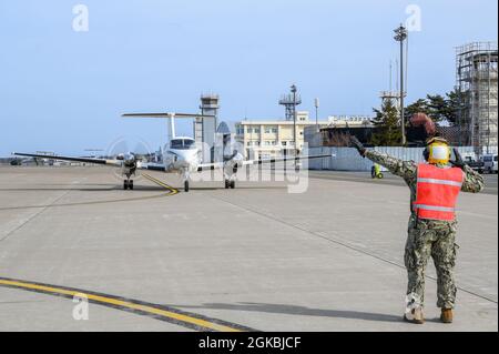 210305-N-EJ241-4056    MISAWA, Japan (March 5, 2021) – Aviation Boatswain’s Mate (Handling) 3rd Class Grant Daniels, assigned to Naval Air Facility (NAF) Misawa, directs the crew of a C-12 Huron during a transportation mission. NAF Misawa provides aviation and ground logistics support and services to all permanent and transient U.S. Navy and U.S. Marine Corps forces in Northern Japan. Stock Photo