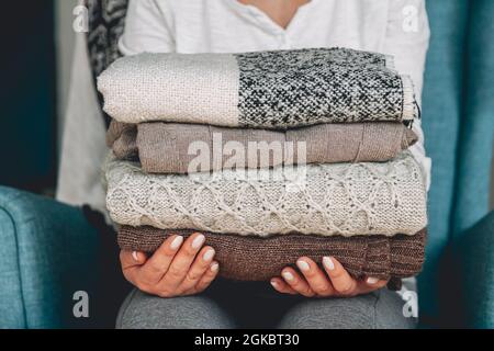 Female hands hold a stack of warm knitted sweaters Stock Photo