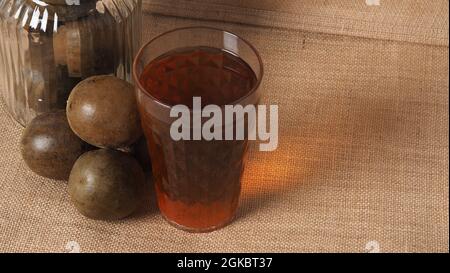 Monk fruit or Luo Han Guo. Dried fruits for healthy sweetener drink. Natural herbal remedy and glass bottle background. Monk fruit drink for who conce Stock Photo