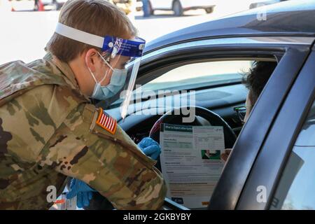 U.S. Army Spc. Zoe Festge, a Mansfield, Ohio, native and combat medic assigned to the 1st Battalion, 70th Field Artillery Regiment, 2nd Armored Brigade Combat Team, 1st Infantry Division, speaks with a COVID-19 vaccine recipient about post-vaccination procedures at the Fair Park Community Vaccination Center (CVC) in Dallas, March 8, 2021. On this International Women’s Day, Festge and her fellow service members from Fort Riley, Kansas, worked hard to provide the underserved communities with vaccine relief support. Medical and logistical 1st Infantry Division Soldiers deployed to Dallas to provi Stock Photo