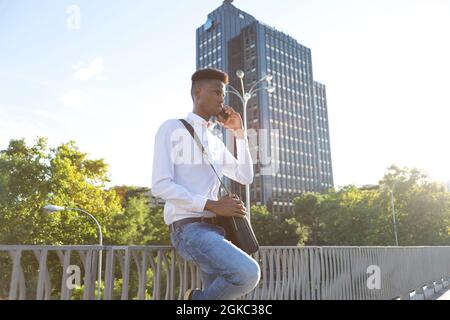 young afro american businessman with briefcase talking on the phone outdoor with sunlight Stock Photo